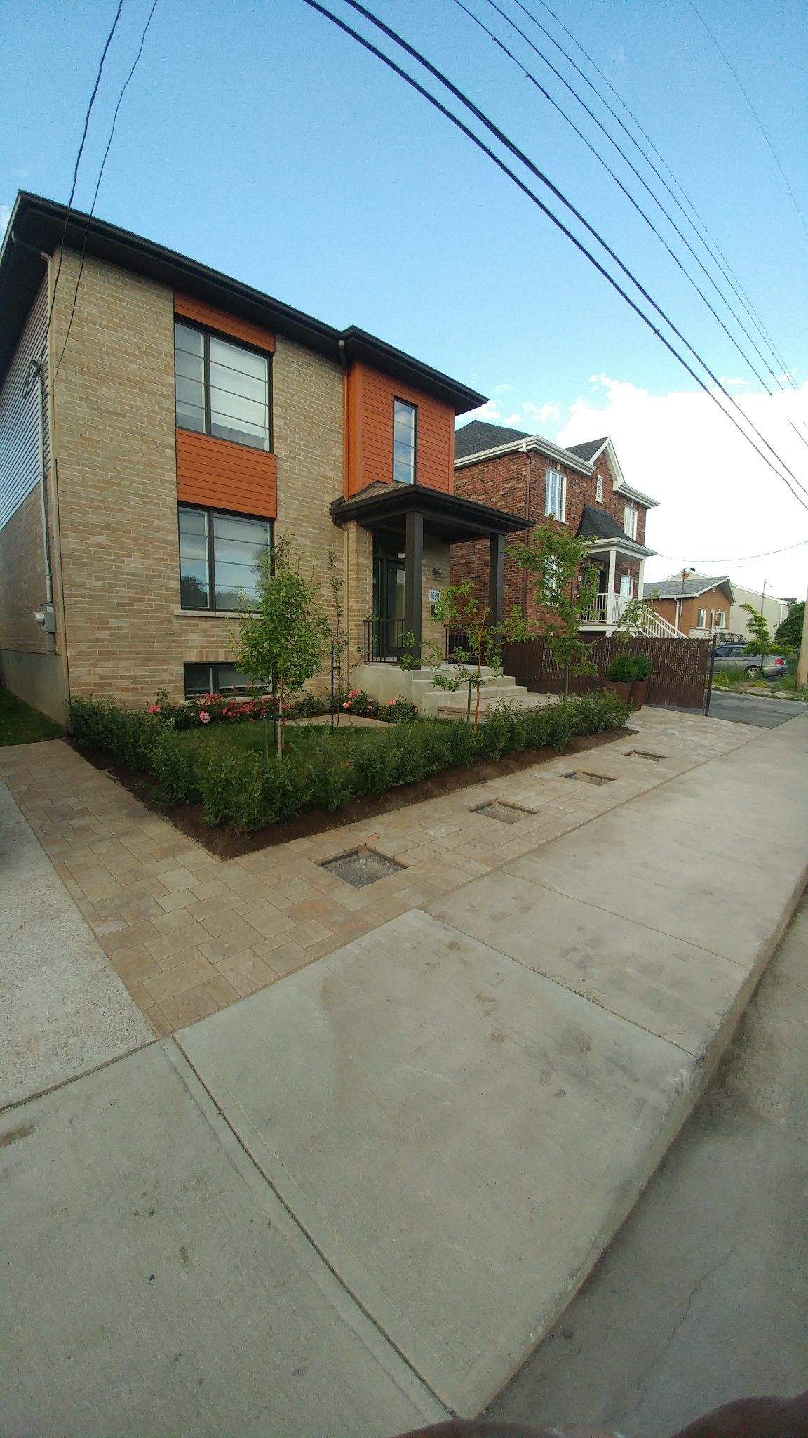 Maison moderne neuve avec pavé tan qui enveloppe l'avant et le côté