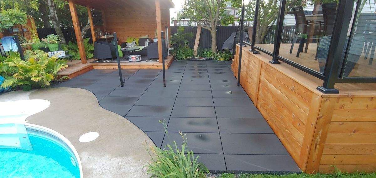 Patio en grandes dalles foncées qui épouse la courbe de la piscine