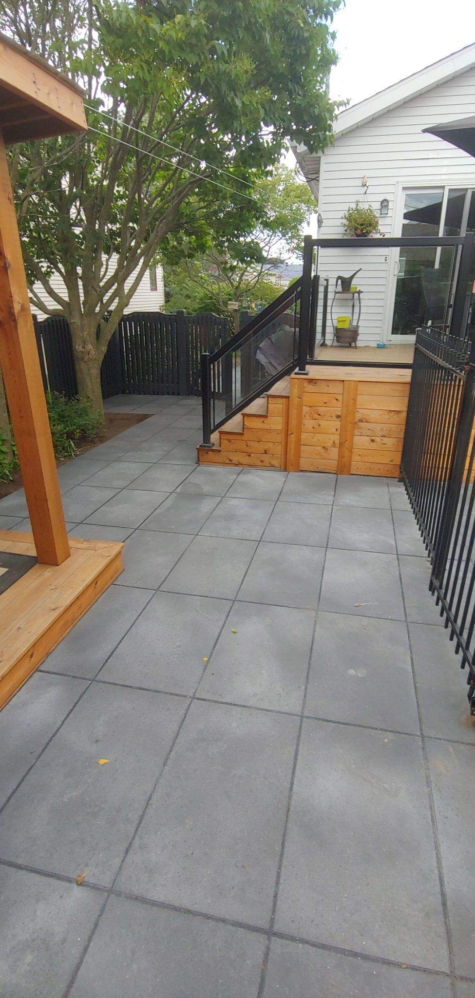 Terrasse en cèdre avec garde-corps en verre, au-dessus du patio en dalles foncées