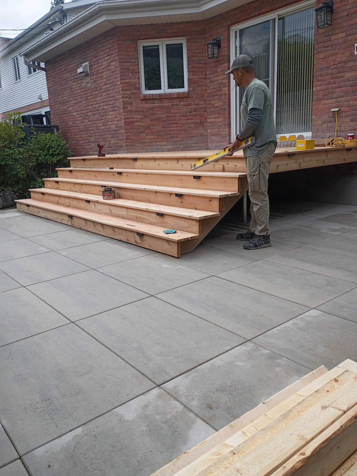 Ouvrier de LT Terrassement qui vérifie le niveau d'un patio en grandes dalles