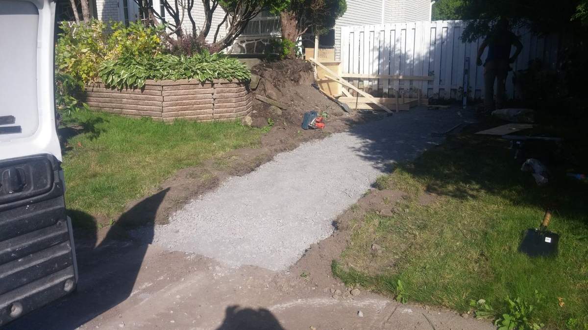 Préparation d'un escalier sur pente : gravier étendu et coffrage au fond