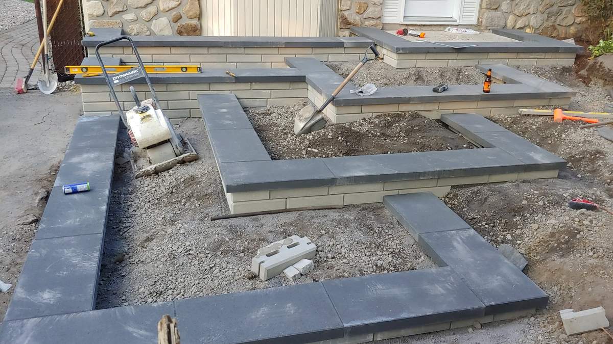 Pendant les travaux : entrée en paliers en construction, capuchons noirs et murs beiges en place, plaque vibrante sur le chantier