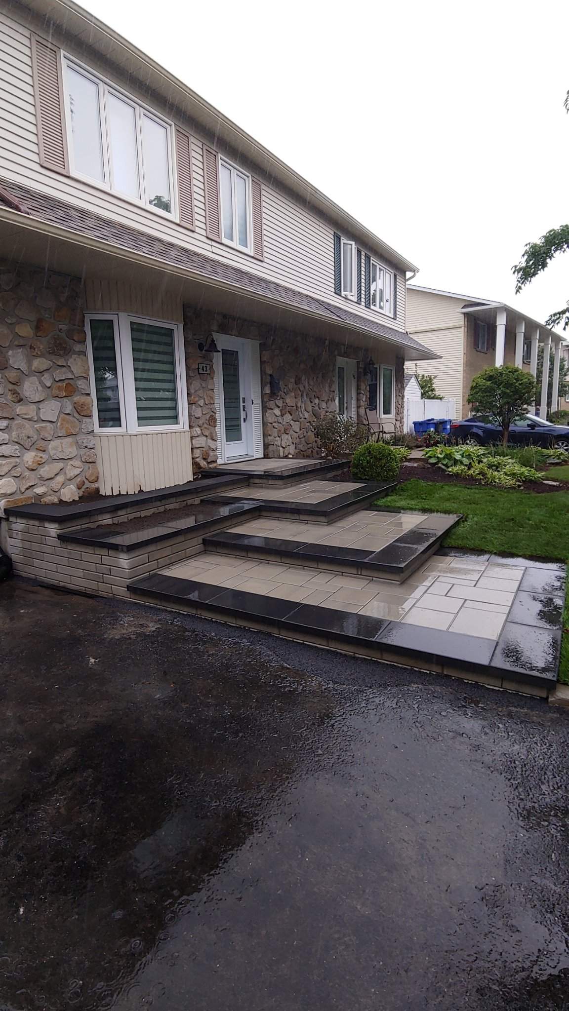 Après : entrée en paliers noir et beige terminée devant le jumelé en pierre, sous la pluie