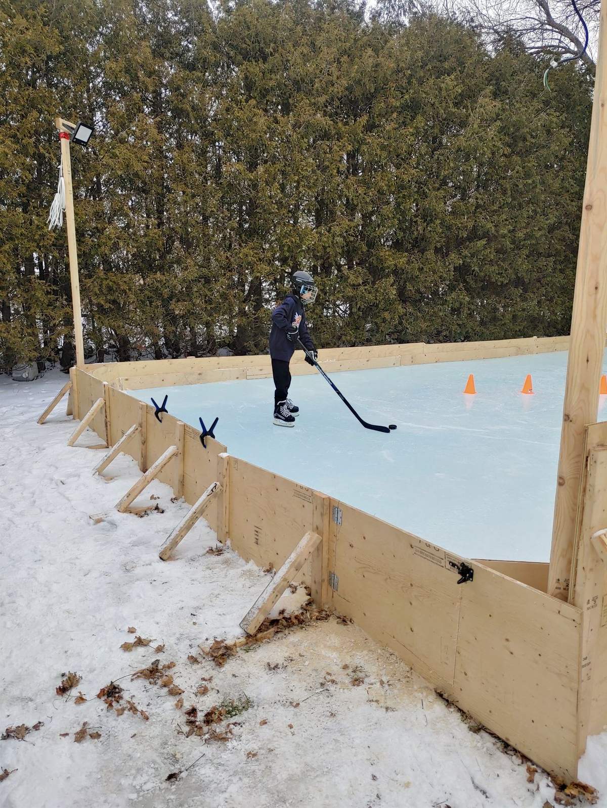 Enfants et famille qui patinent sur la patinoire de cour en plein jour