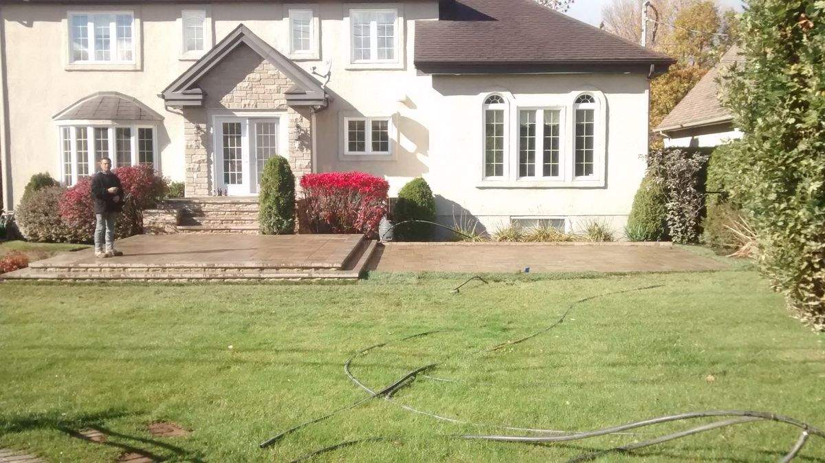 Terrasse arrière relevée en pavé, arbustes rouges d'automne