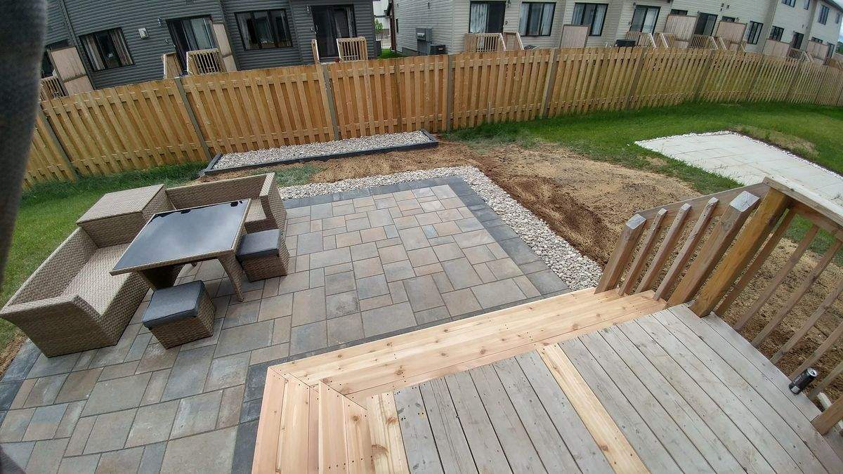 Cour arrière d'une maison de ville neuve, patio en pavé à bordure foncée