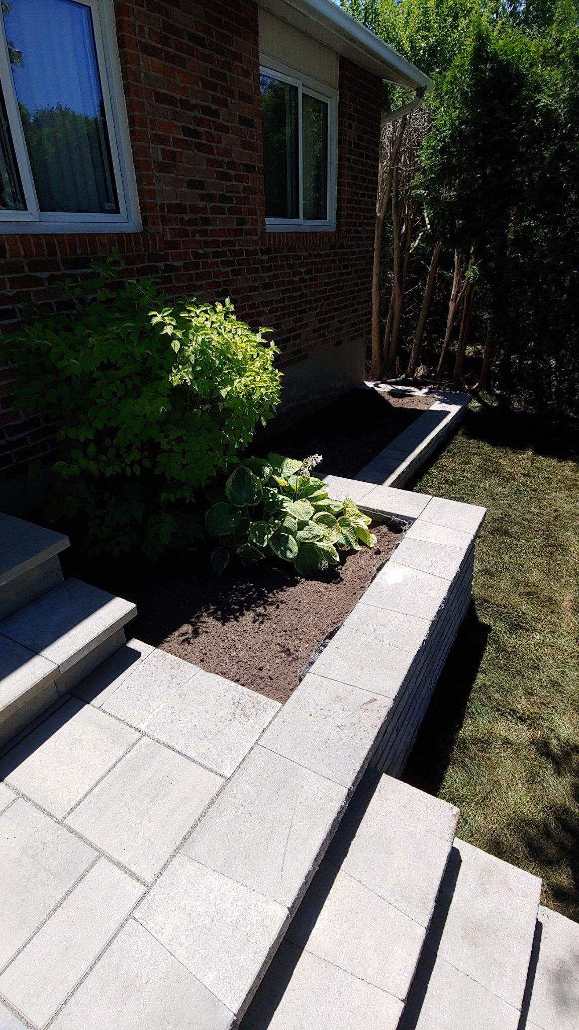 Terrasse avant relevée avec murets et quatre marches, bungalow en brique
