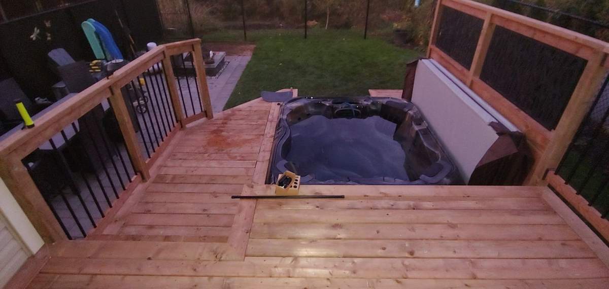Terrasse en cèdre construite autour d'un spa, au crépuscule